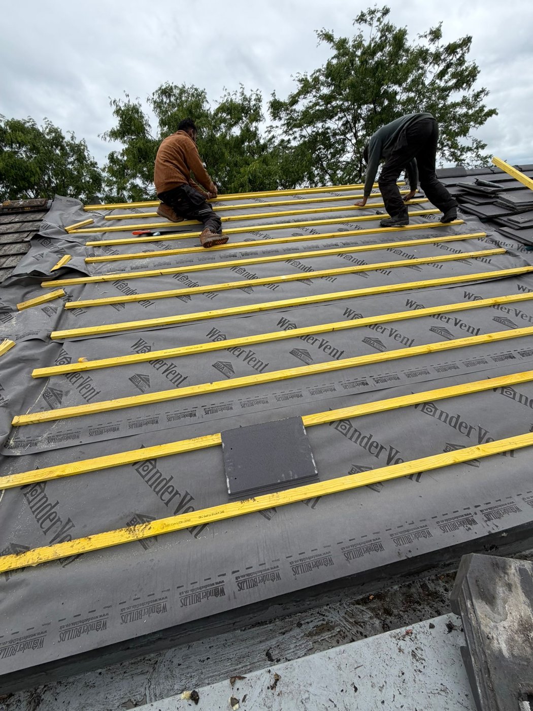 Roofers working above newly installed roof underlay and battens