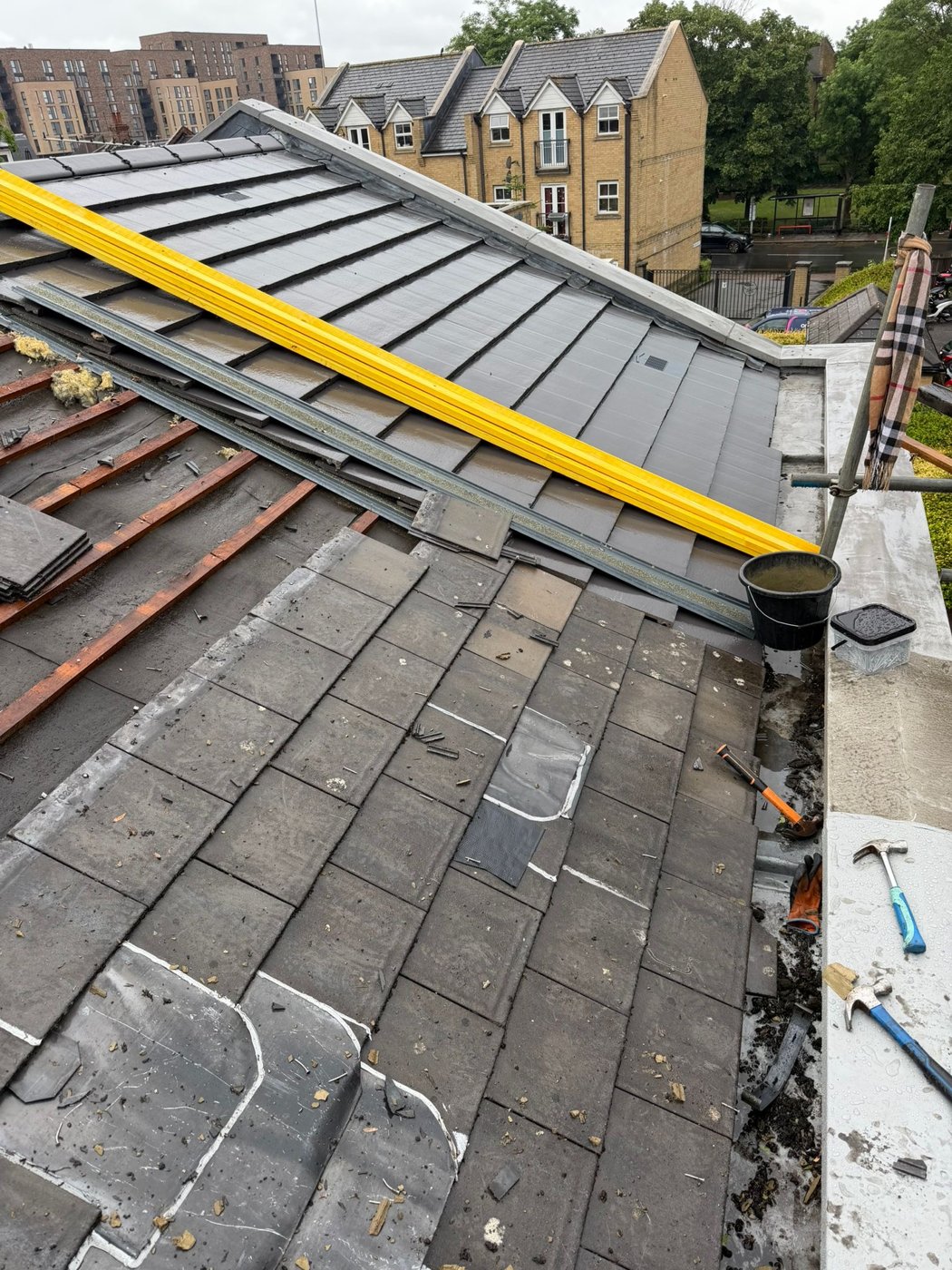 New dark roof covering being fitted beside exposed battens