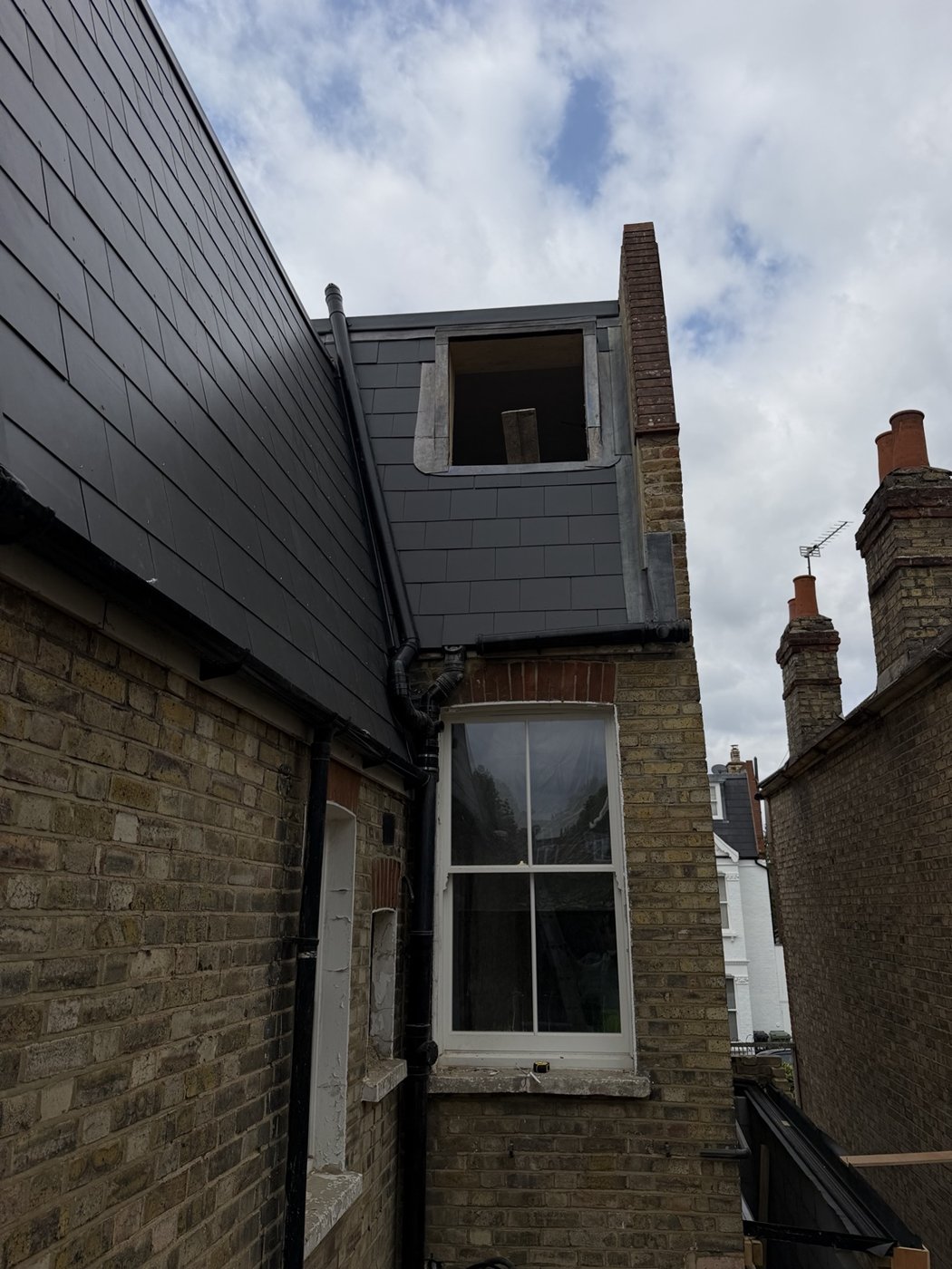 Slate-style roofing and cladding around an unfinished opening with scaffolding